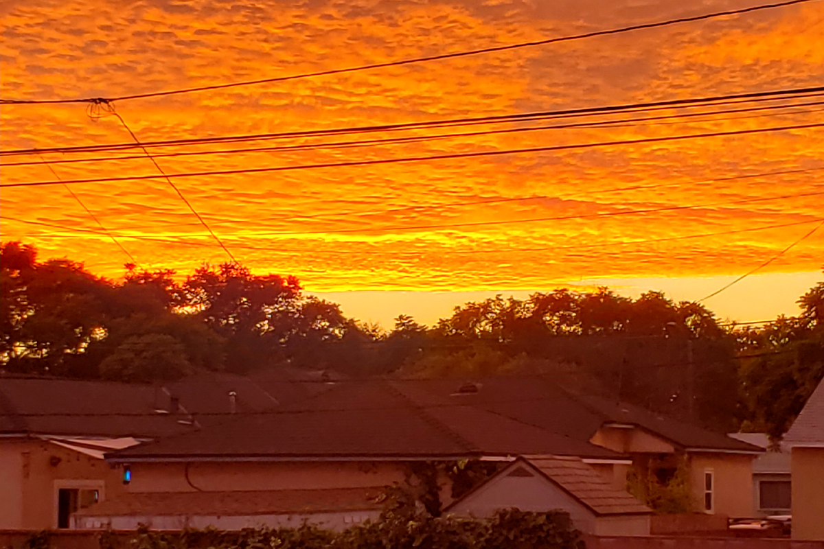 A sunset over a suburan develpment, with orange and yellow clouds